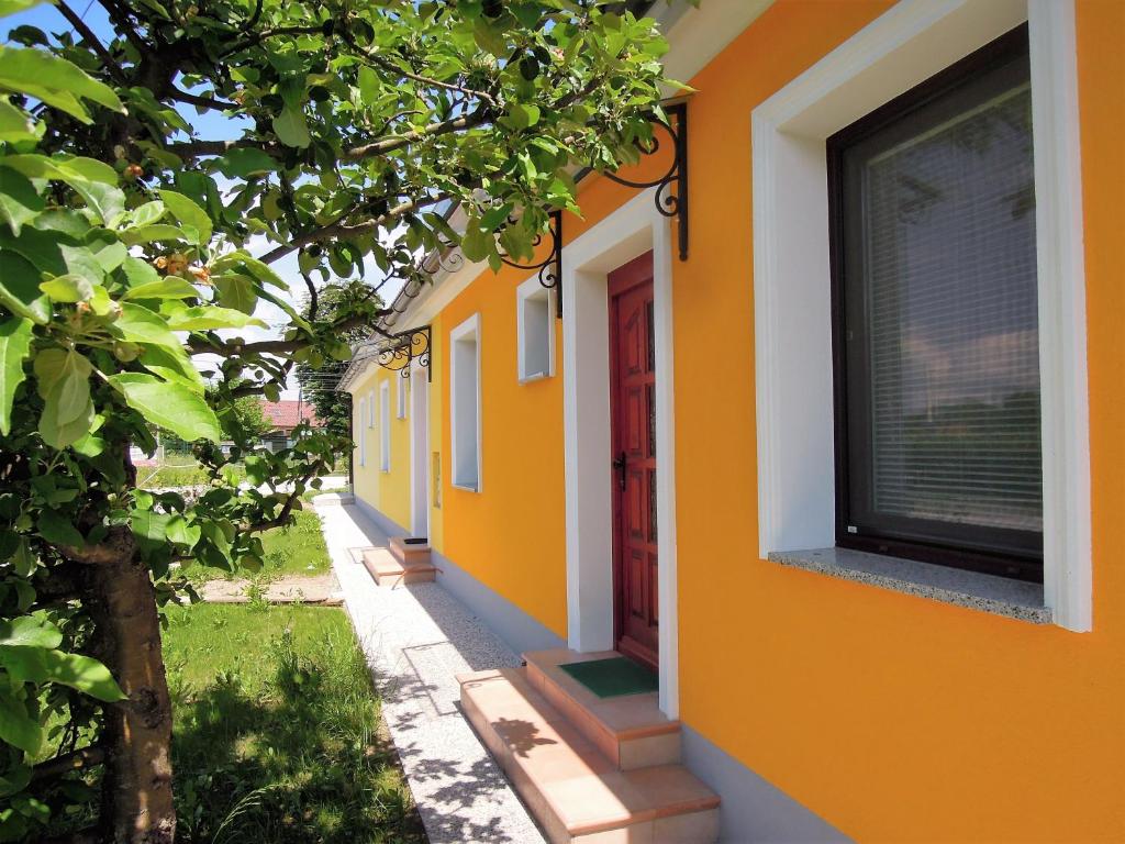 ein orangefarbenes Gebäude mit einer roten Tür und einem Baum in der Unterkunft Apartment Antonia in Dobova