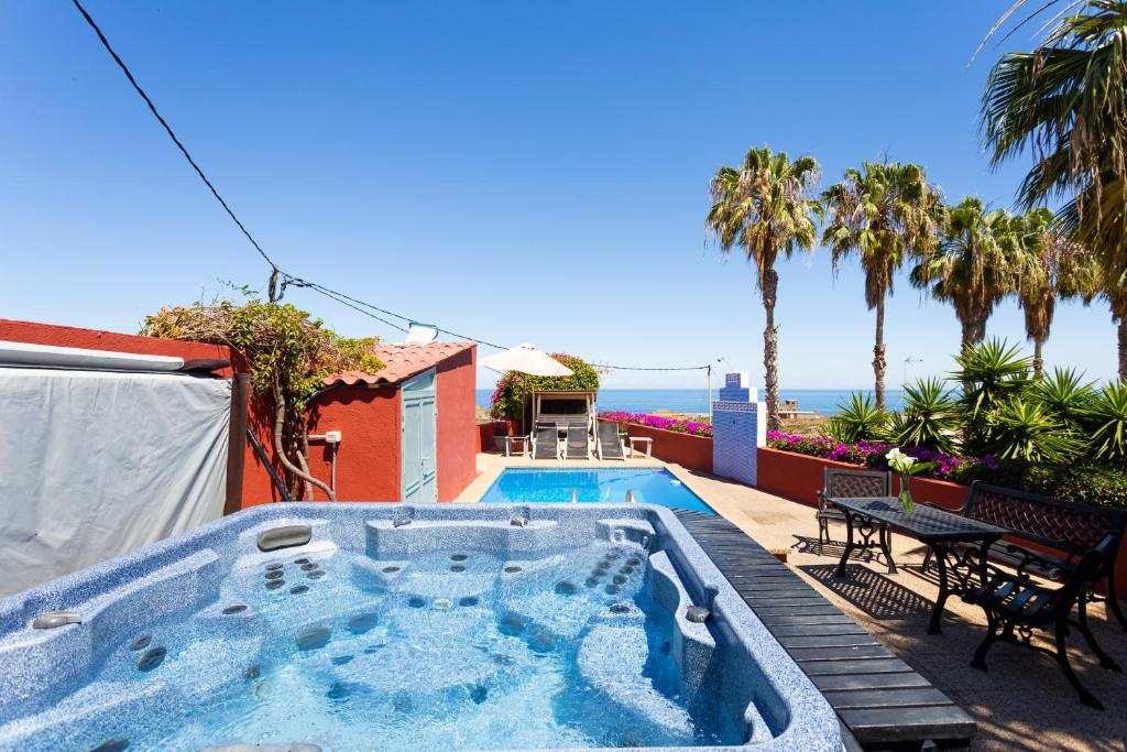 a house with a swimming pool with palm trees and the ocean at Finca La Gaviota - El Rincon-Jacuzzi con vistas al teide in Icod de los Vinos