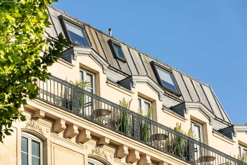 a building with a balcony on top of it at Hotel Marais Grands Boulevards in Paris