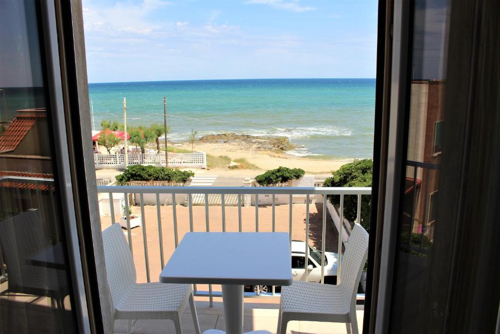 balcón con mesa y sillas y vistas a la playa en Appartamenti Costa dei Trulli en Torre Canne