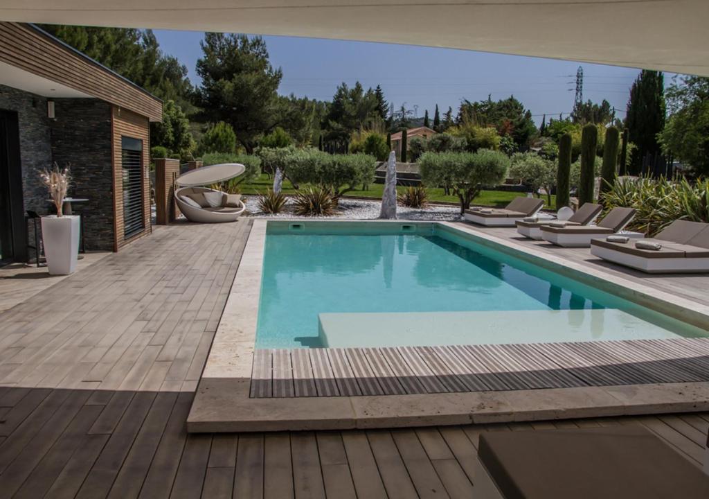 a swimming pool with lounge chairs next to a house at Mas des Cigales in Orgon