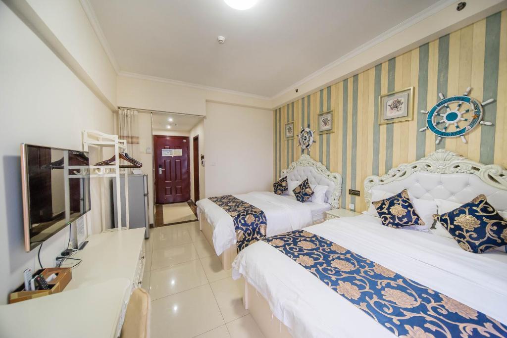 a hotel room with two beds and a television at Xing Yu Legend Service Apartment Canton Fair Branch in Guangzhou