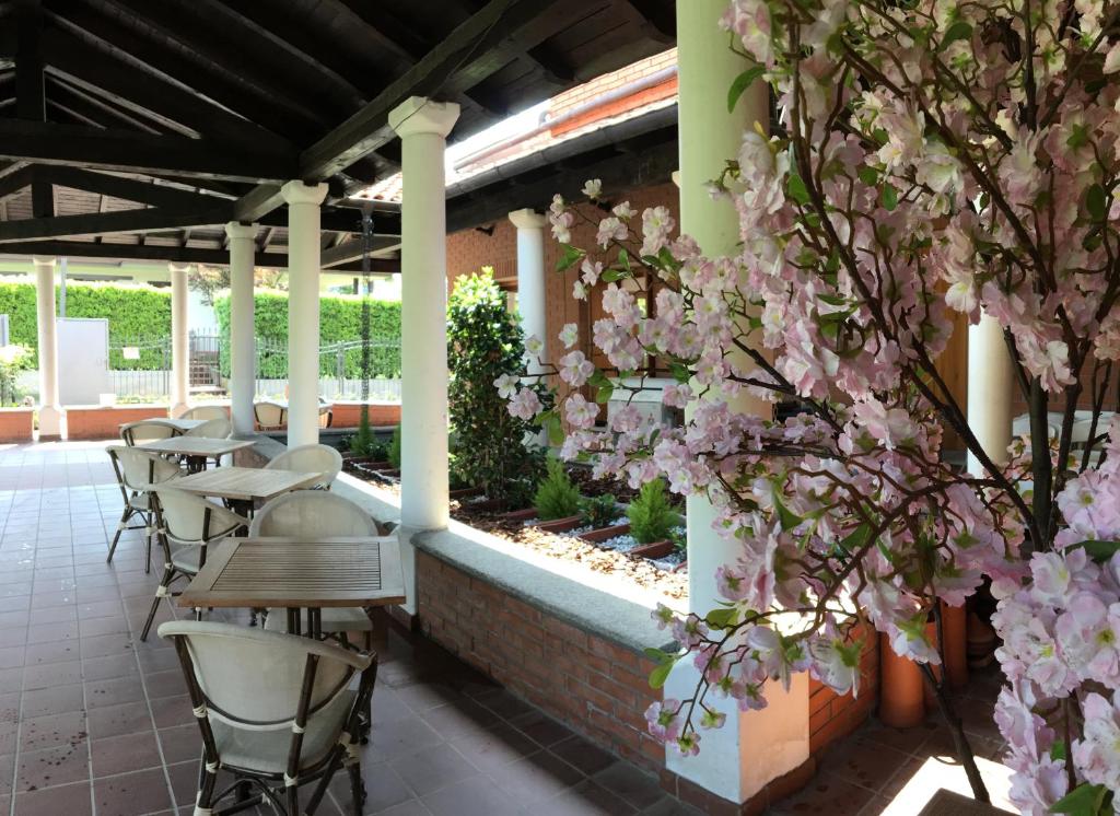 a patio with tables and chairs and pink flowers at Ostello Casa Emmaus in Maccagno Inferiore