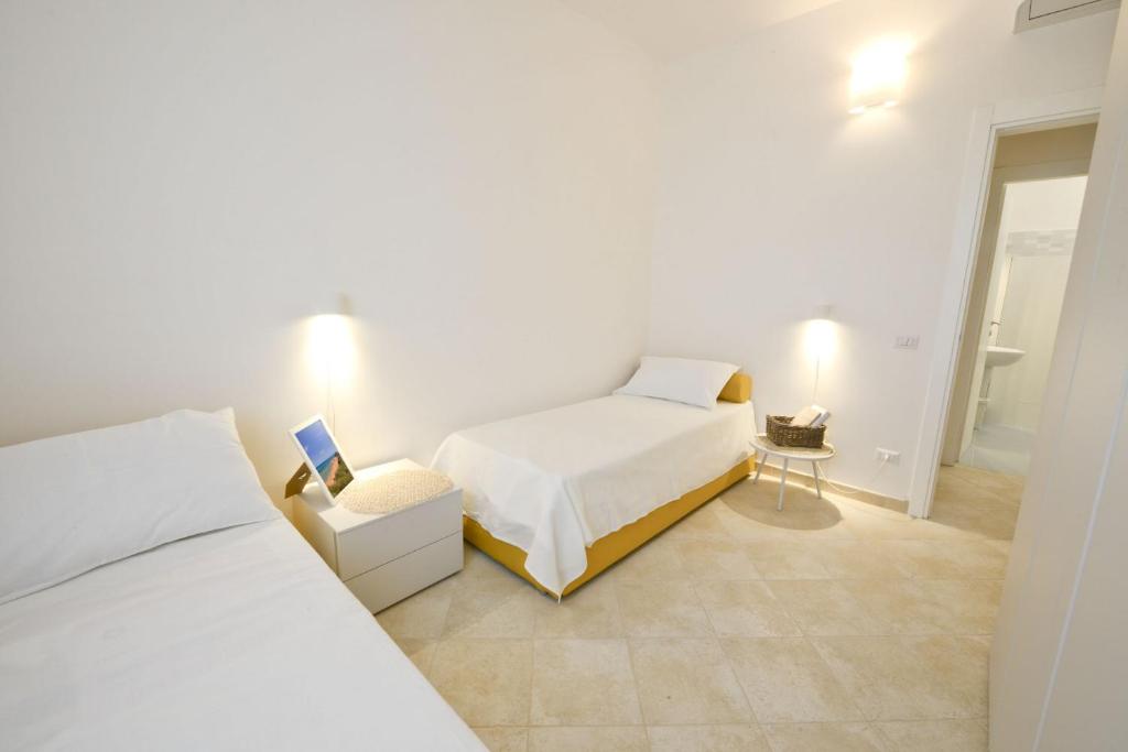 a white bedroom with two beds and a bathroom at Blue Sea Villas by Wonderful Italy in Ostuni