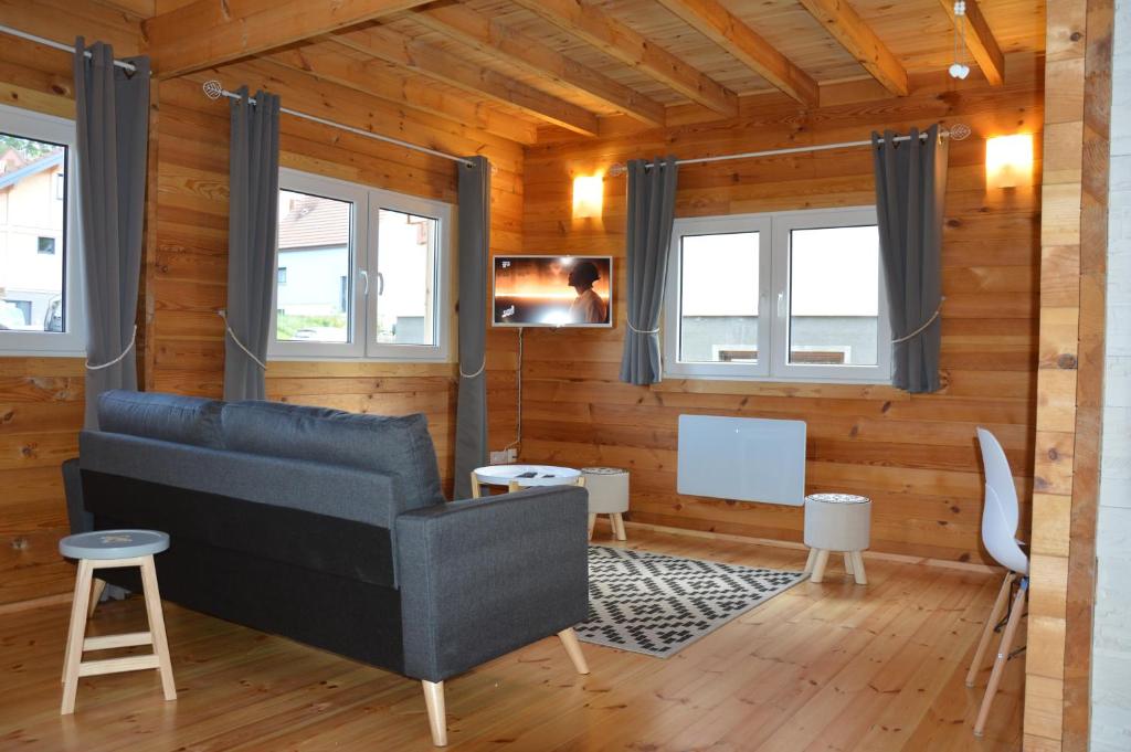 a living room with a couch and two windows at Chalet Les Prés in Neubois