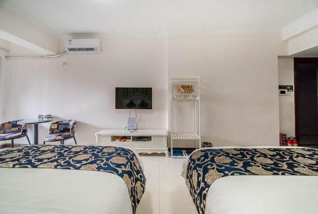 a bedroom with two beds and a tv on the wall at Xing Yu Legend Service Apartment Canton Fair Branch in Guangzhou