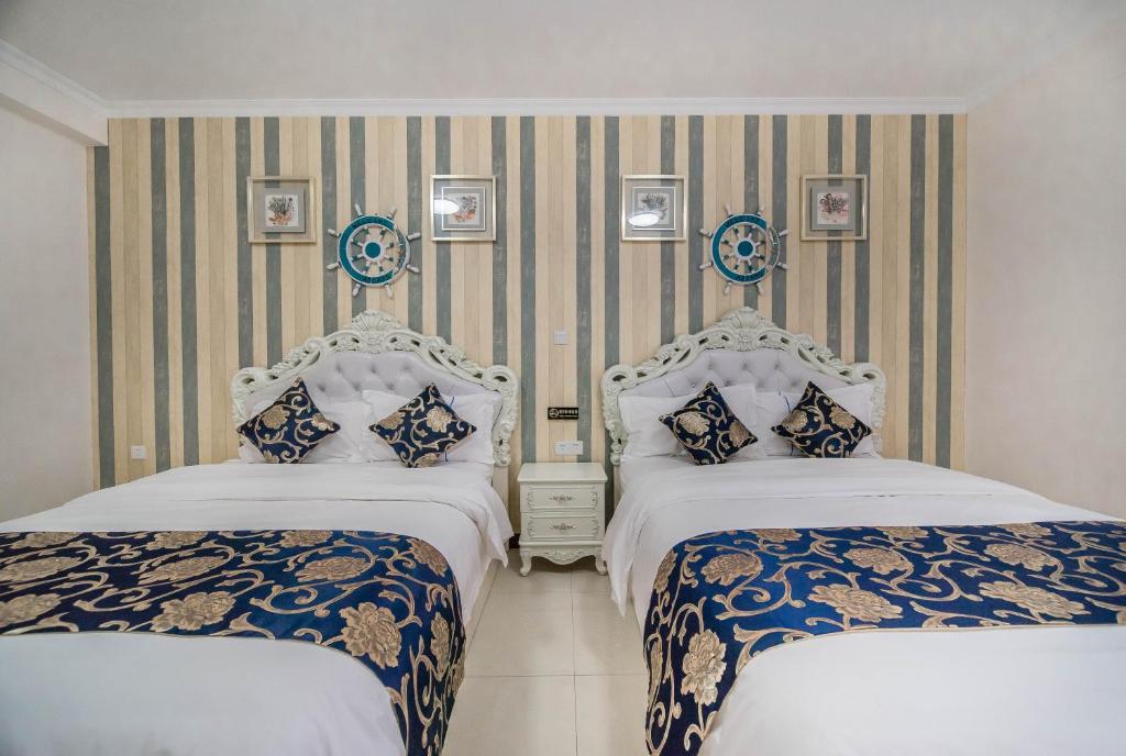 two beds in a hotel room with two bedsitures at Xing Yu Legend Service Apartment Canton Fair Branch in Guangzhou