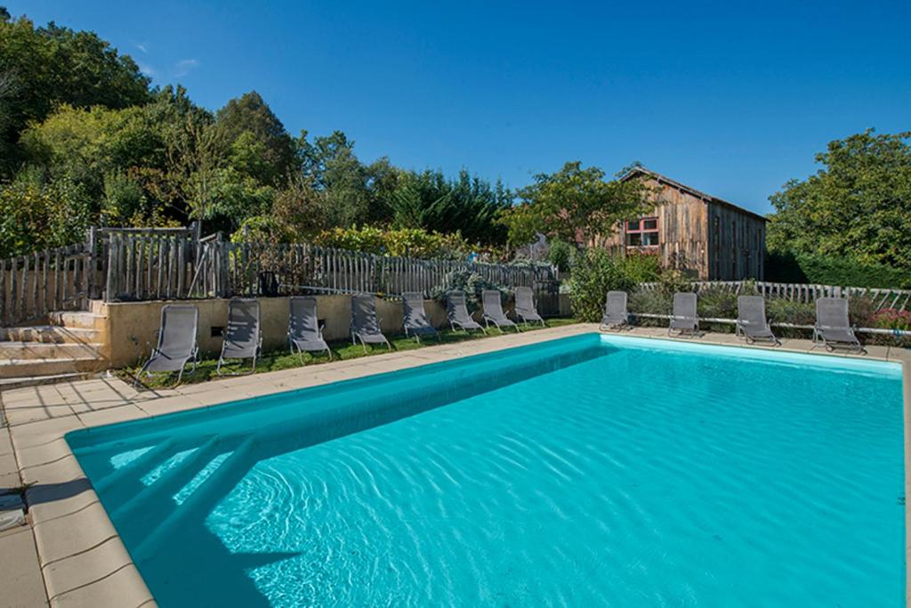 a swimming pool with chairs and a fence at Le Domaine De Pecany in Paleyrac