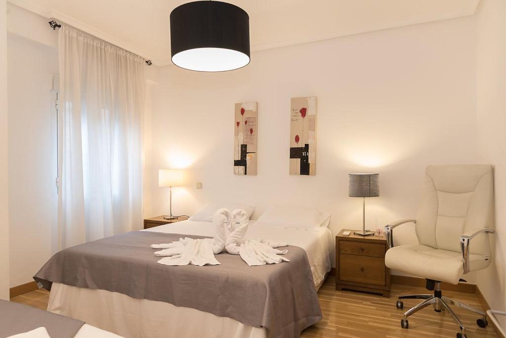 Plaza Mayor - 5 minutos andando في مدريد: غرفة نوم بسرير مع شراشف بيضاء وكرسي