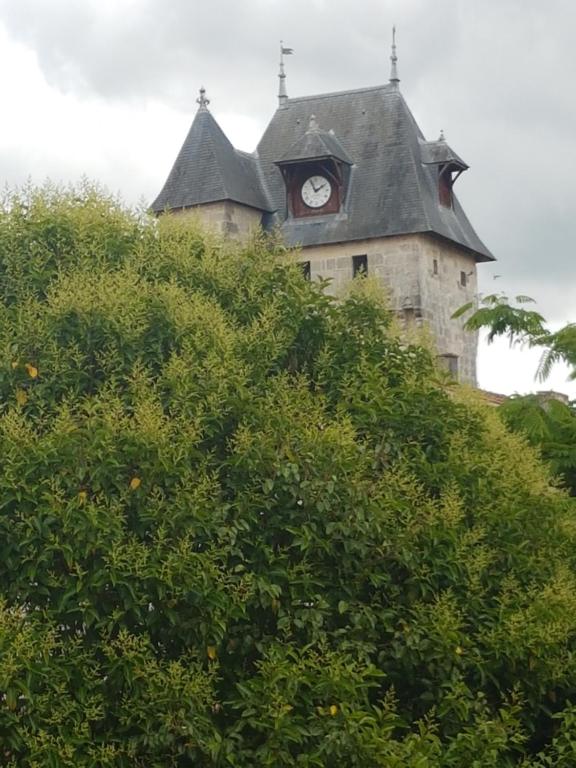 un edificio con una torre de reloj en la cima de una colina en La Laverie, en Saint-Jean-dʼAngély