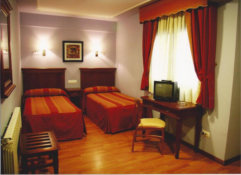 Habitación con 2 camas y escritorio con TV. en Hostal Torres, en San Leonardo de Yagüe