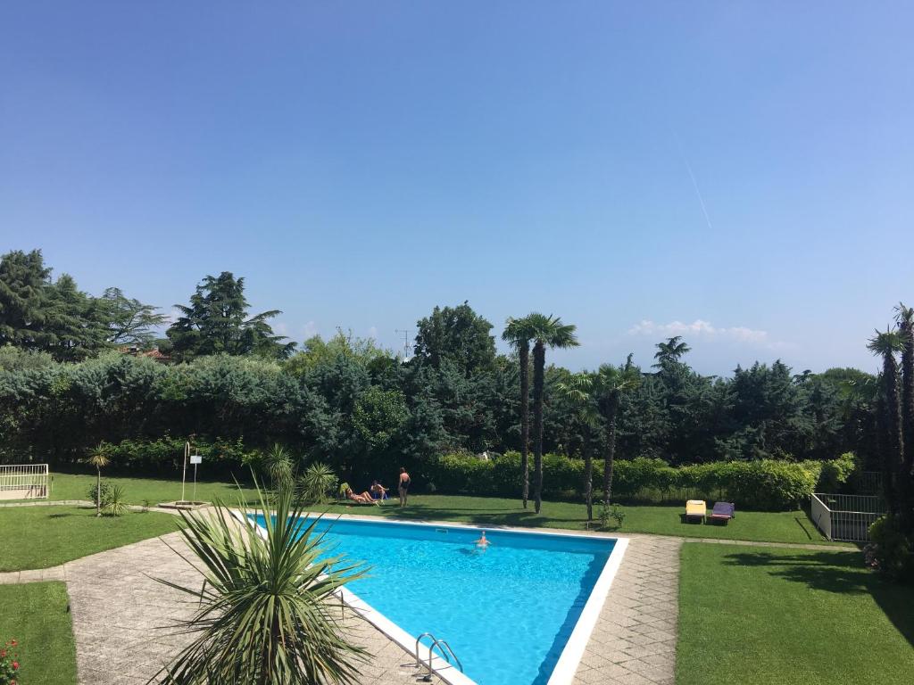 une piscine dans un jardin planté de palmiers dans l'établissement Green Garda Desenzano, à Desenzano del Garda