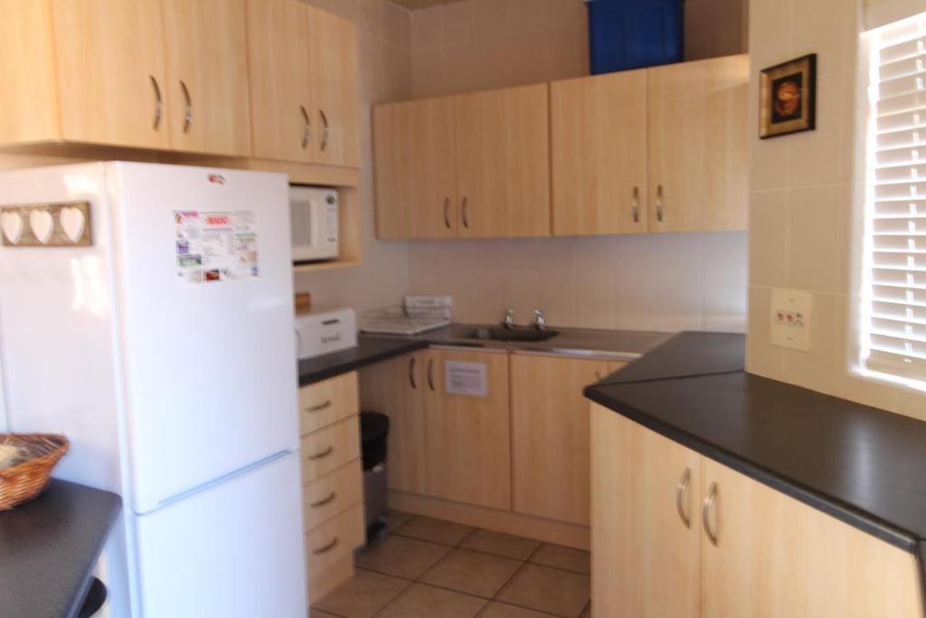 eine Küche mit Holzschränken und einem weißen Kühlschrank in der Unterkunft Seeskulp 10 in Margate