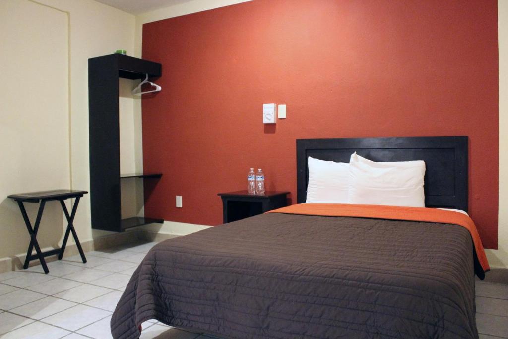 a bedroom with a bed with a red wall at Hotel Maya Becan in Campeche