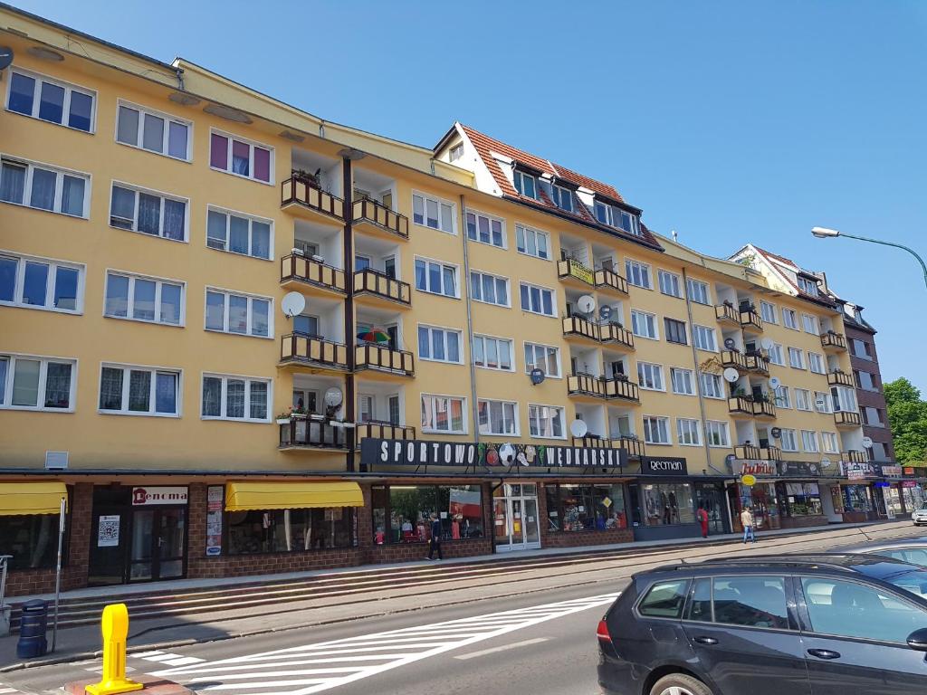 duży żółty budynek z balkonami na ulicy w obiekcie Apartament Mieszko Kołobrzeg w Kołobrzegu