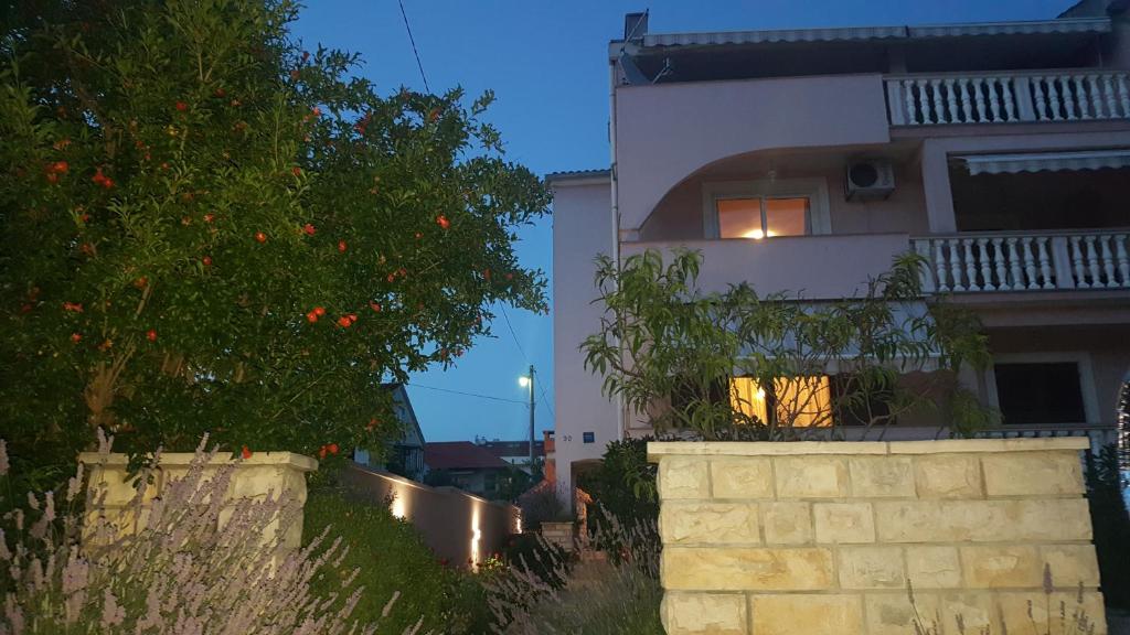 ein Haus mit einem Baum und einer Wand davor in der Unterkunft Apartmani Lucija in Zadar