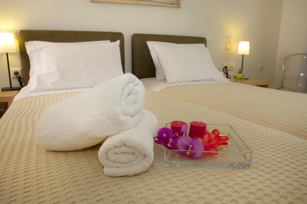 a white towel and a bowl of flowers on a bed at Ilion Spa Hotel in Loutra Edipsou