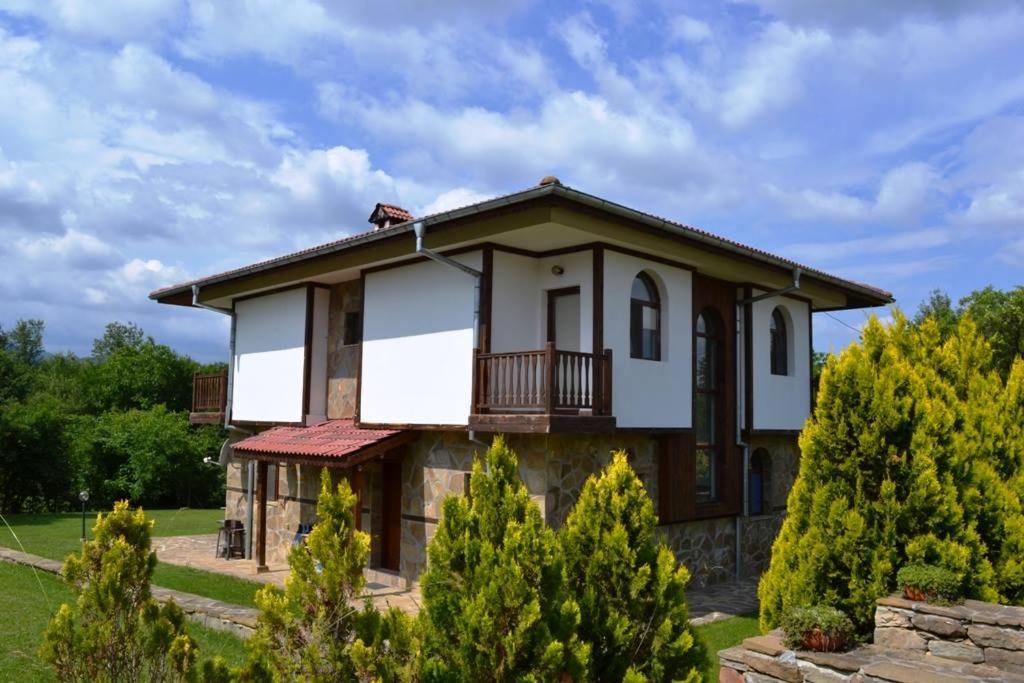 a large house with a balcony and trees at Sichanova Guest House in Brŭchkovtsi