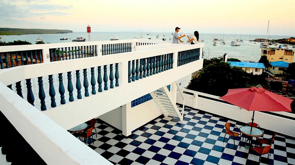 a balcony with a table and an umbrella and the water at Galapagos Family Vacation 3 bedrooms 7 guests Centrally located and ocean view in Puerto Ayora