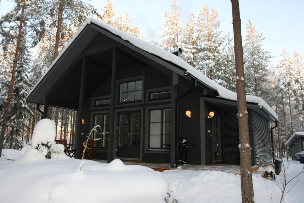 uma cabana negra na floresta na neve em Ähtärin lomamökit - ONNI Mökki em Inhantehtaat