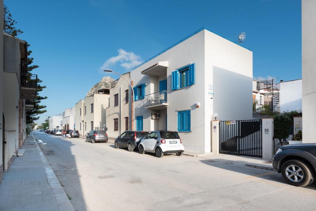 una strada con auto parcheggiate davanti agli edifici di Reef and Dream a San Vito lo Capo