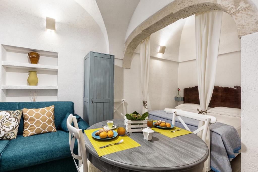 una sala da pranzo con tavolo e divano blu di Dimora Zafferano - Guest House Ostuni a Ostuni