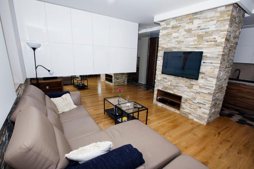 a living room with a couch and a stone fireplace at Apartament "Park Lotników" in Krakow