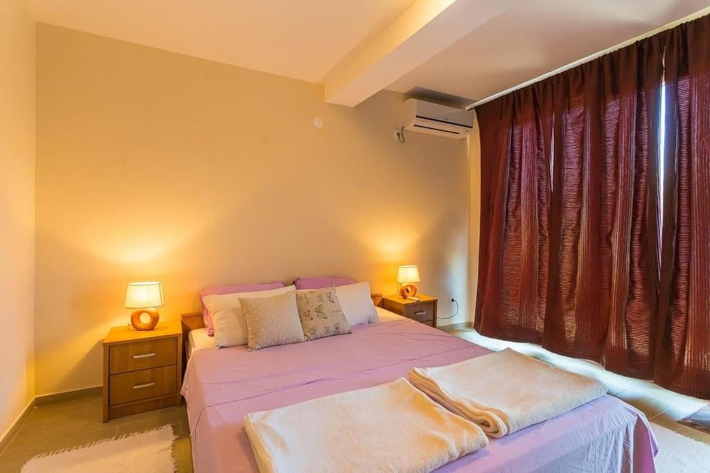 a bedroom with a purple bed with two lamps and a window at Fresh & spacious studio in Dubrovnik