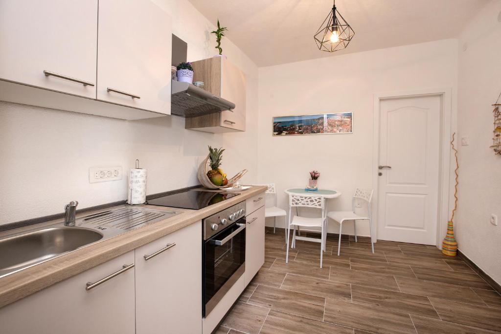 - une cuisine avec des placards blancs, un évier et une table dans l'établissement Apartment Barka, à Split
