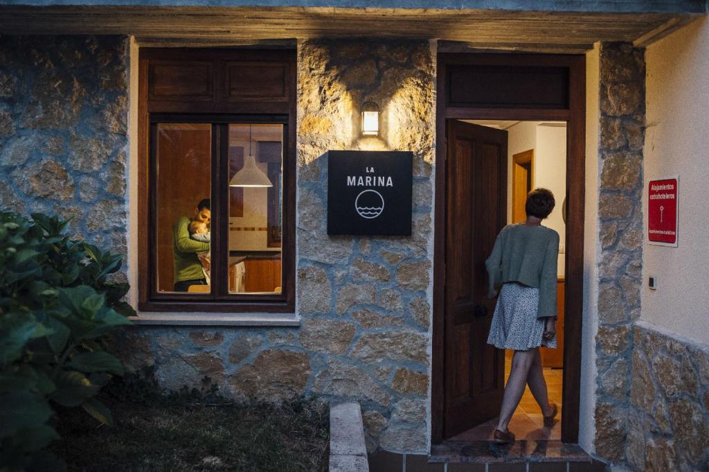 Una mujer saliendo por la ventana de un edificio en The Cantabrian Apartamentos, en Serdió