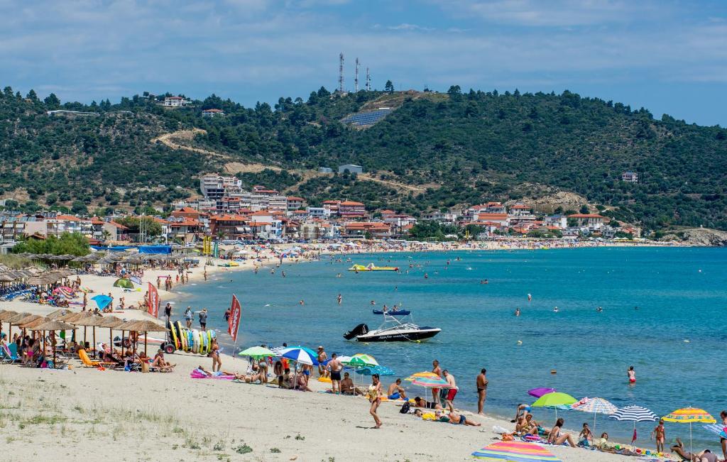 a crowded beach with people and a boat in the water at House Katerina Mediterranean in Sarti