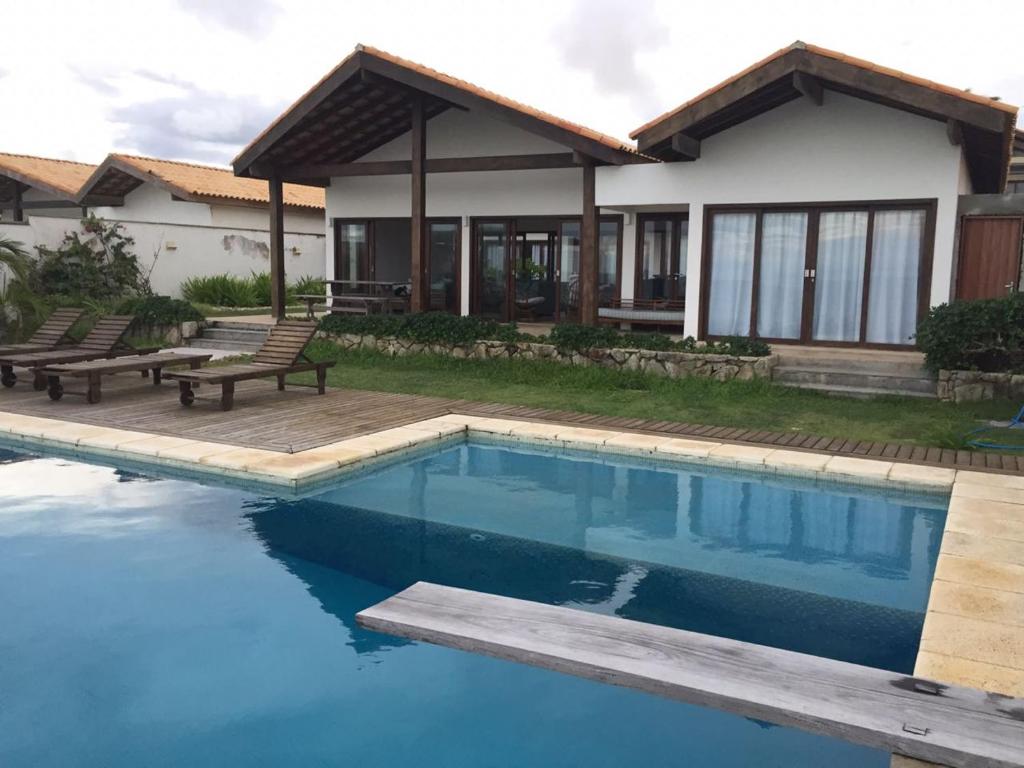 uma casa com piscina e dois bancos em Villa 06 - Taiba Beach Resort - TBR em São Gonçalo do Amarante