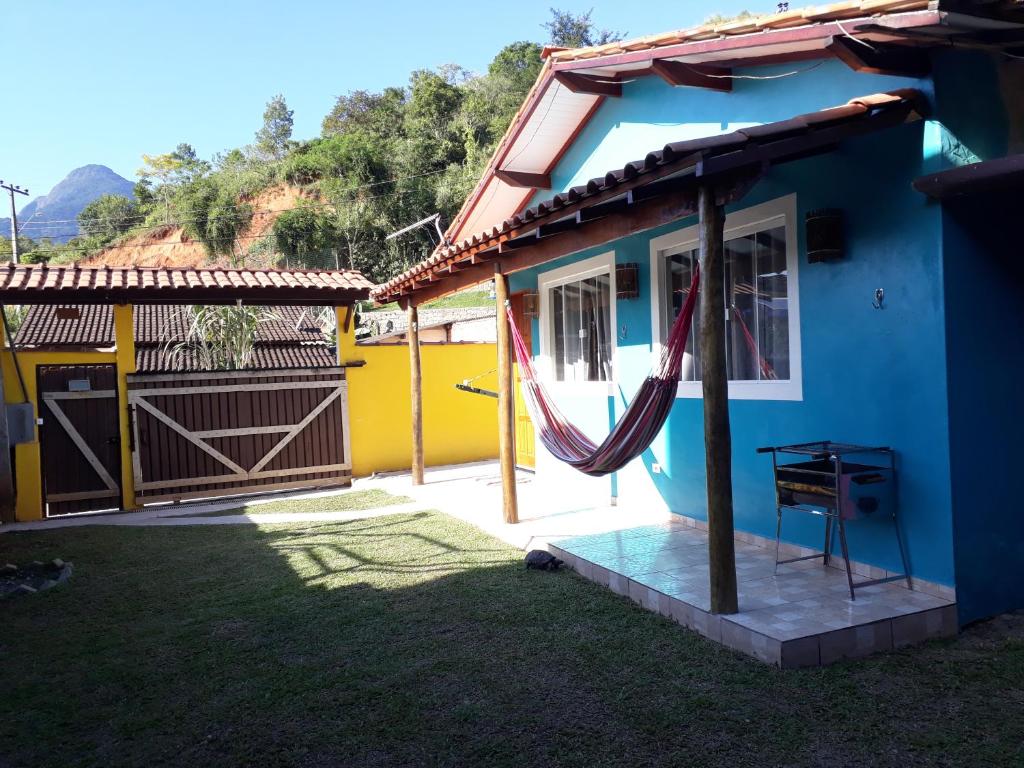 a blue house with a hammock outside of it at Chalé Canto do Galo in Ilhabela