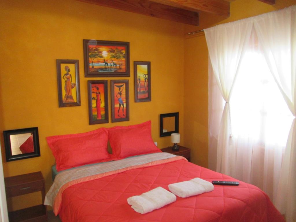 1 dormitorio con 1 cama roja y 2 toallas en Tiny House Atacama, en San Pedro de Atacama