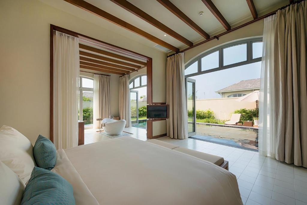 a bedroom with a white bed and a large window at FLC Luxury Resort Samson in Sầm Sơn