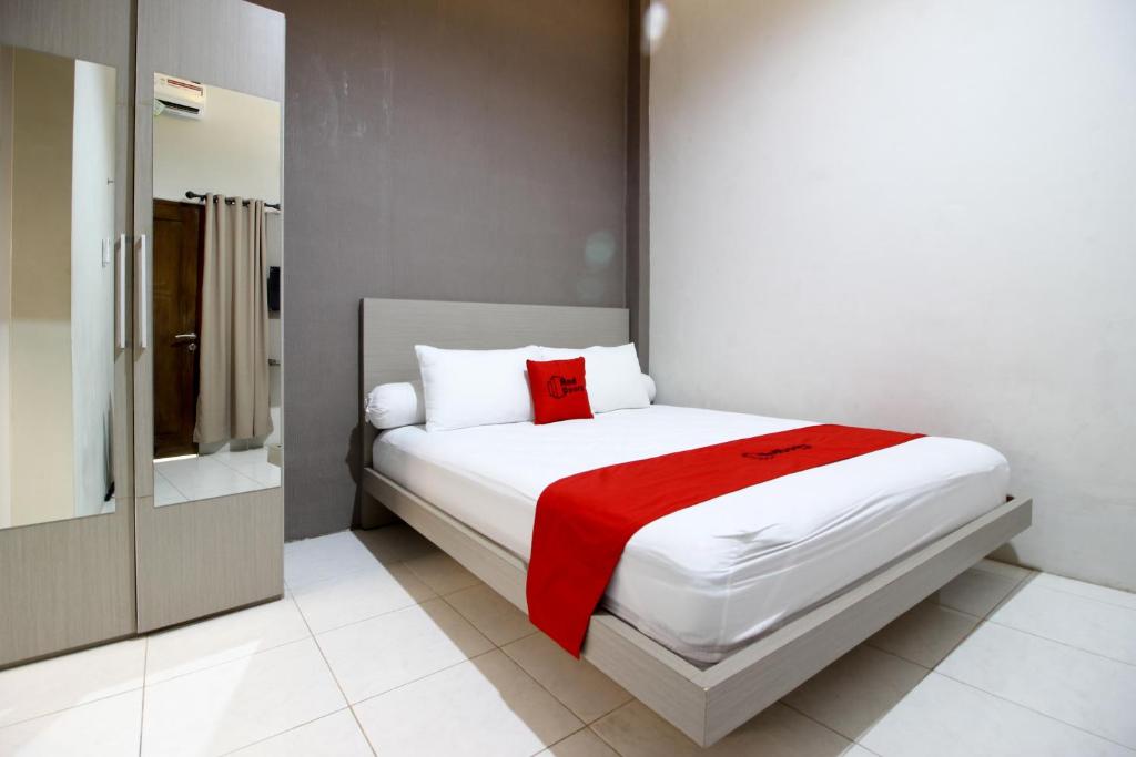 a bedroom with a white bed with a red blanket at RedDoorz Plus near UPN Jogjakarta 2 in Yogyakarta