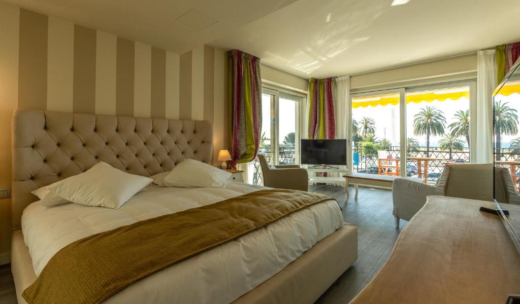 a bedroom with a large bed and a living room at La Dolce Vita Hotel in Menton