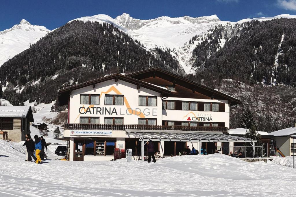 un lodge de esquí con gente parada en la nieve en Catrina Lodge en Disentis