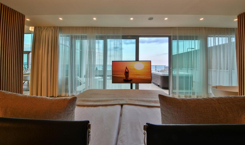 a living room with a tv and a large window at Flamingo Grand Hotel & Spa in Albena