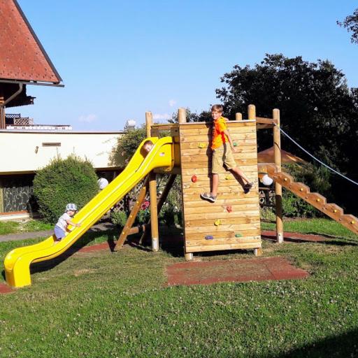 a man is climbing on a wooden play structure at Gasthof Thomann in Velden am Wörthersee