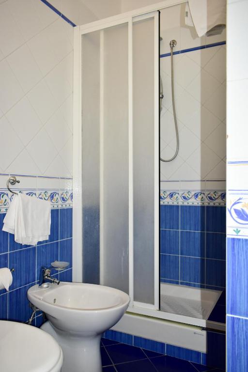a blue and white bathroom with a toilet and a shower at Hotel Amyclae in Sperlonga