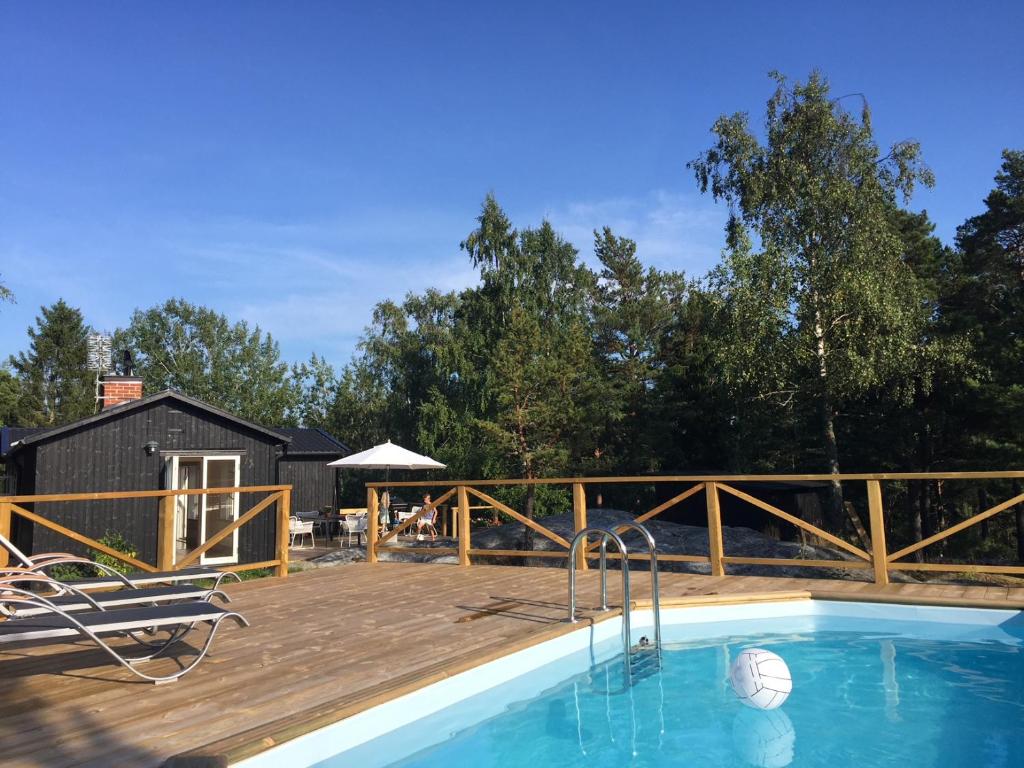 un patio con piscina y terraza de madera en Archipelago-house with pool, boat and bikes, en Djurhamn