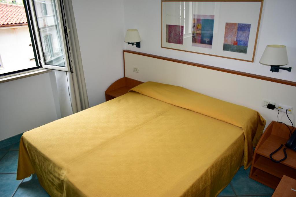 a yellow bed in a room with a window at Hotel Amyclae in Sperlonga