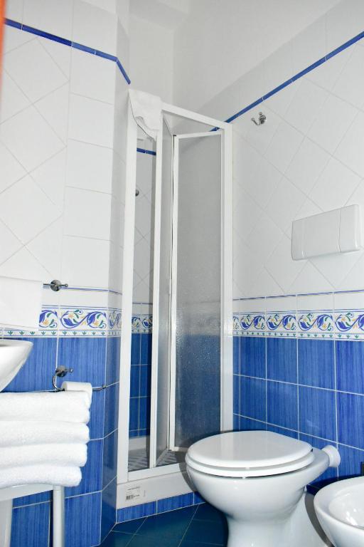a blue and white bathroom with a toilet and a shower at Hotel Amyclae in Sperlonga
