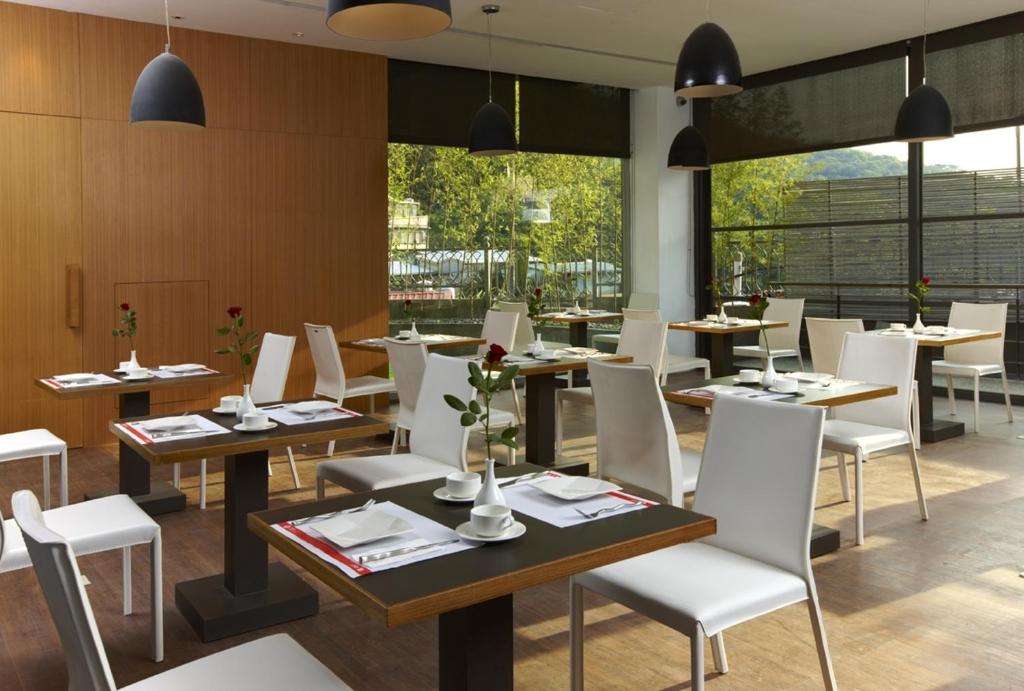 a restaurant with tables and white chairs and windows at Hotel Double One in Taipei