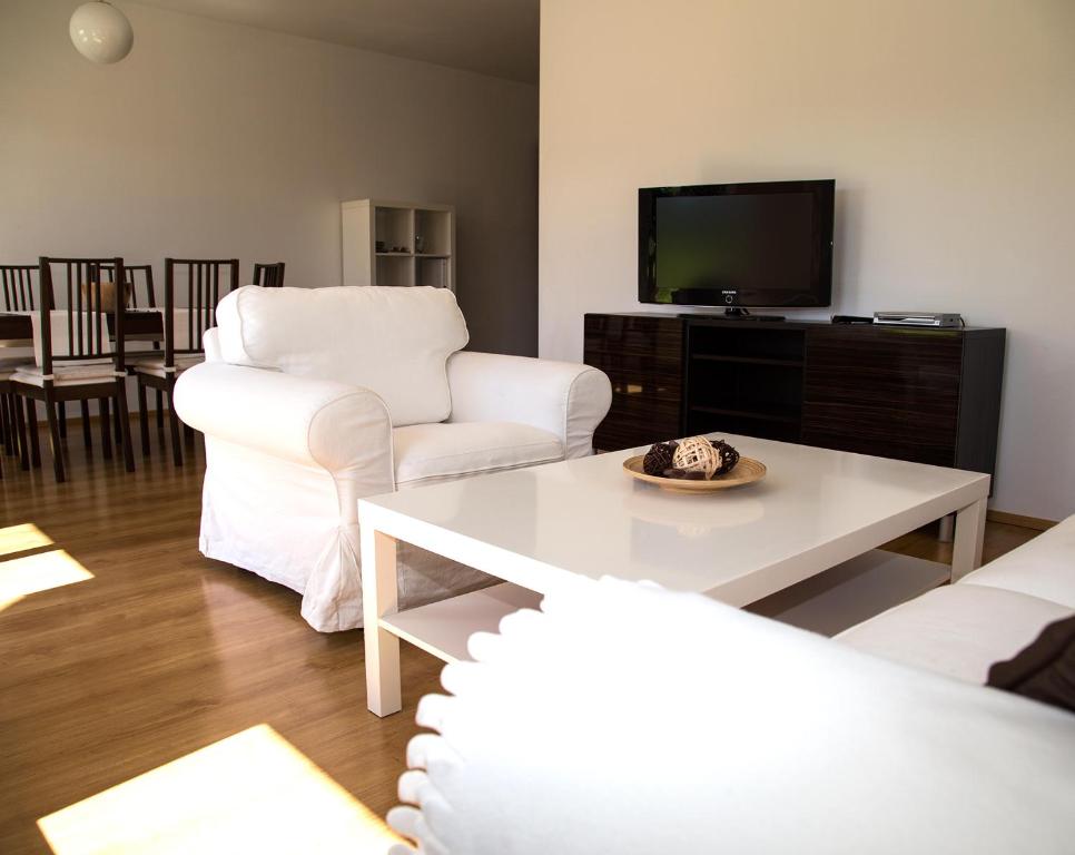 a living room with two white chairs and a tv at Apartments am Turiawald in Schiefling am See