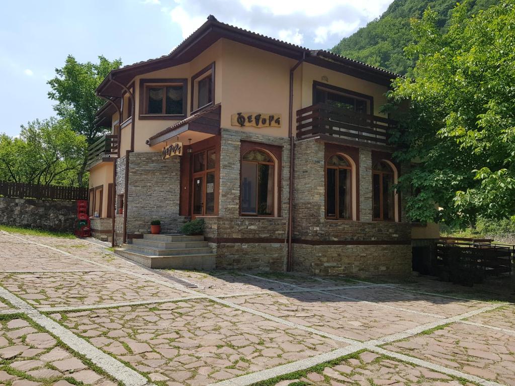 a house on a stone road in front of a building at Family Hotel Fedora in Ribarica