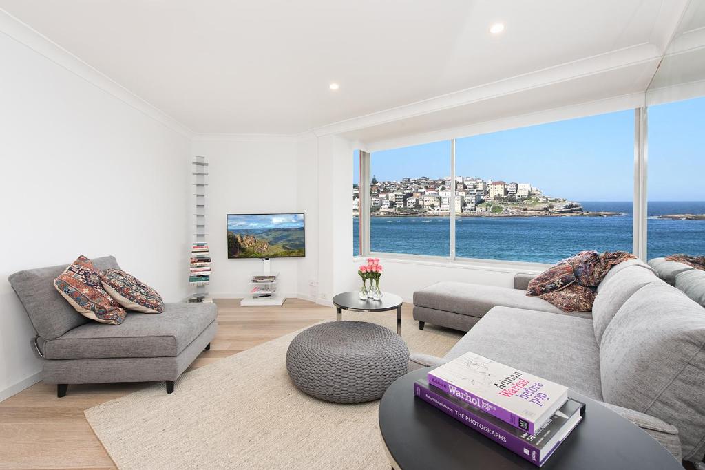 ein Wohnzimmer mit einem Sofa und Stühlen sowie einem großen Fenster in der Unterkunft Right on Bondi in Sydney