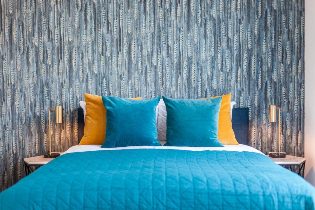 1 cama azul con almohadas azules y papel pintado en KSpace @ The Point en Sheffield