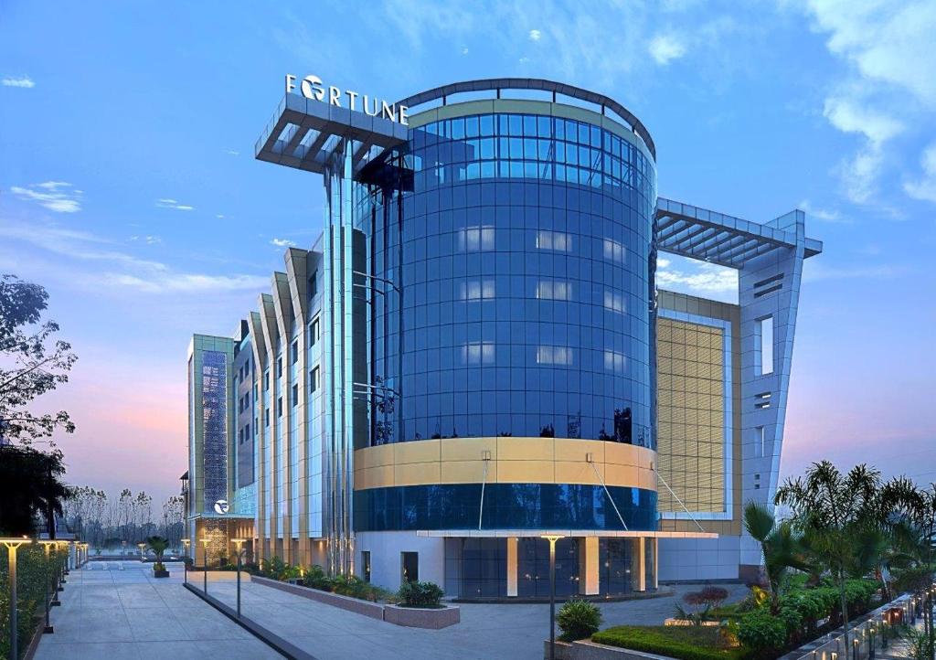 un gran edificio de cristal en una ciudad al atardecer en Fortune Park, Haridwar - Member ITC's Hotel Group, en Haridwar